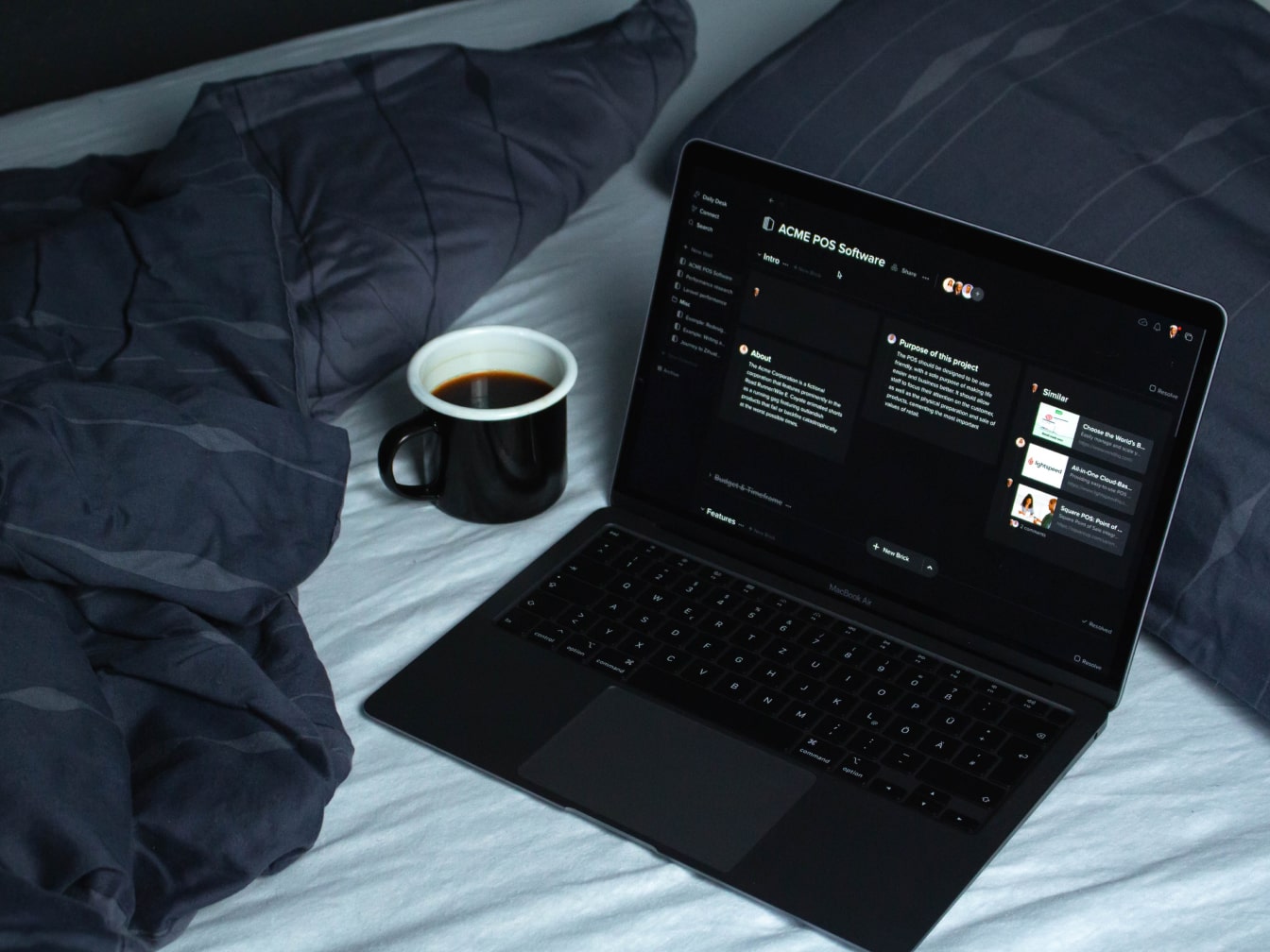 A laptop on a bed with a cup of coffee.