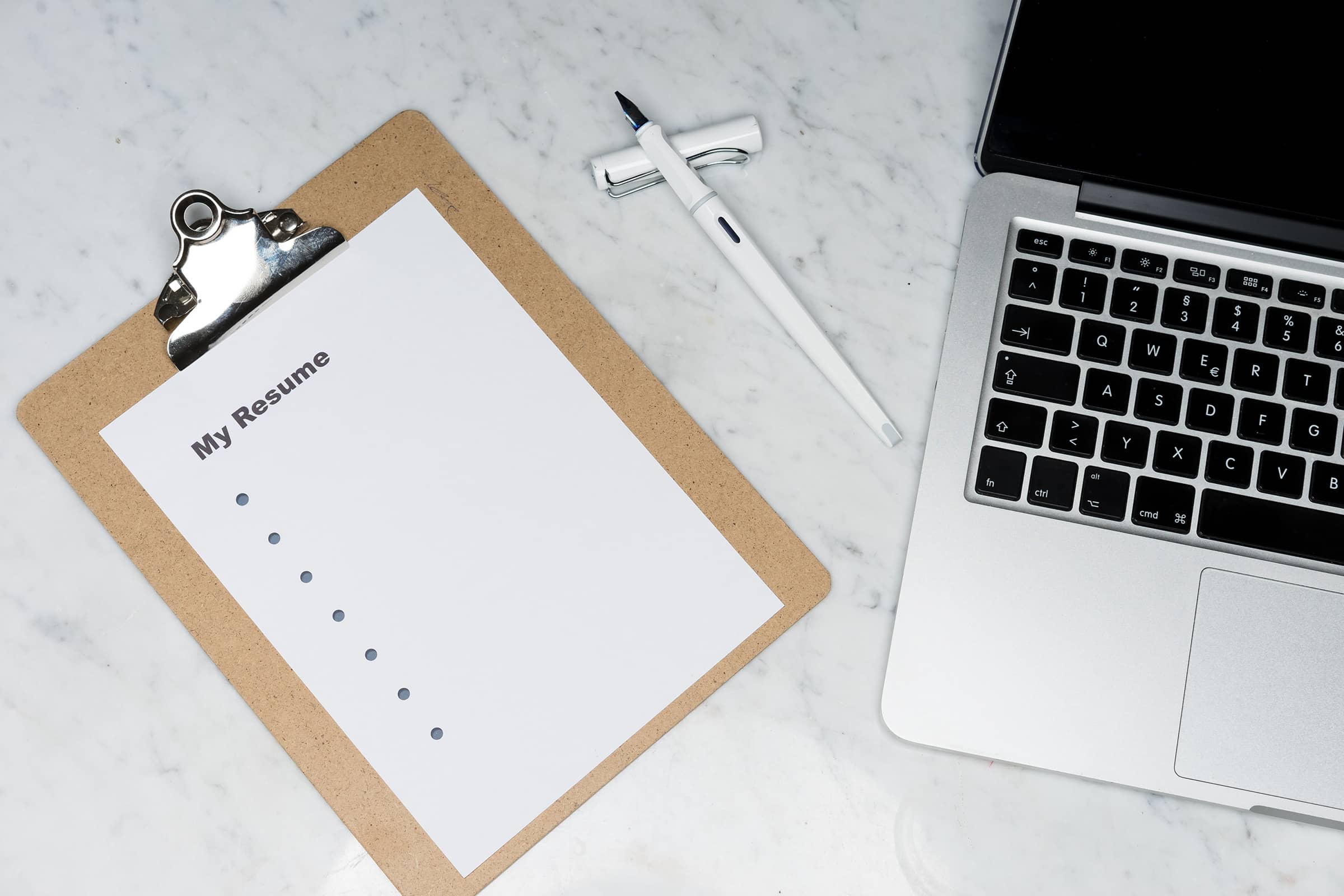 A clipboard with a notepad next to a laptop.