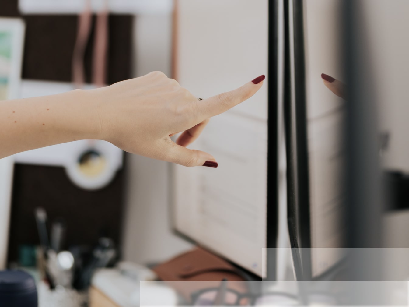 a woman's hand pointing at a computer screen.